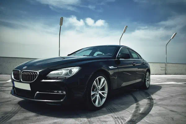 BMW Gran Coupe at three-quarter angle on a controlled rooftop, signalling executive arrival and departure work